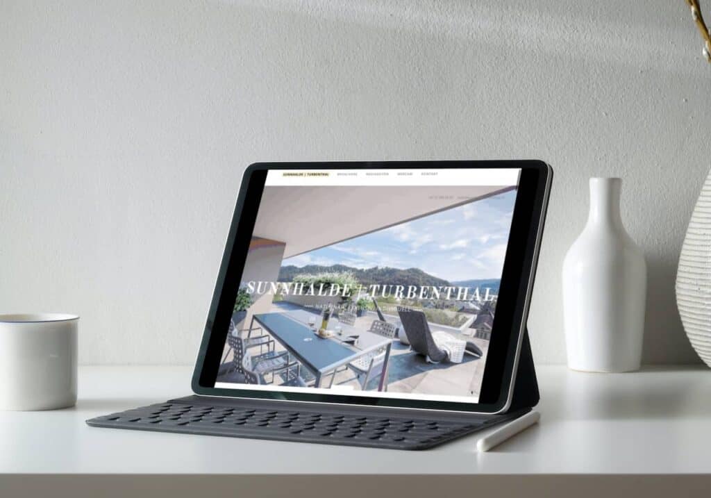 Eine Webseite mit einem iPad, das auf einem Tisch neben einer Vase angezeigt wird.